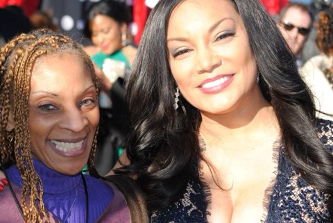 Two smiling women together outdoors at an event, one in a purple top