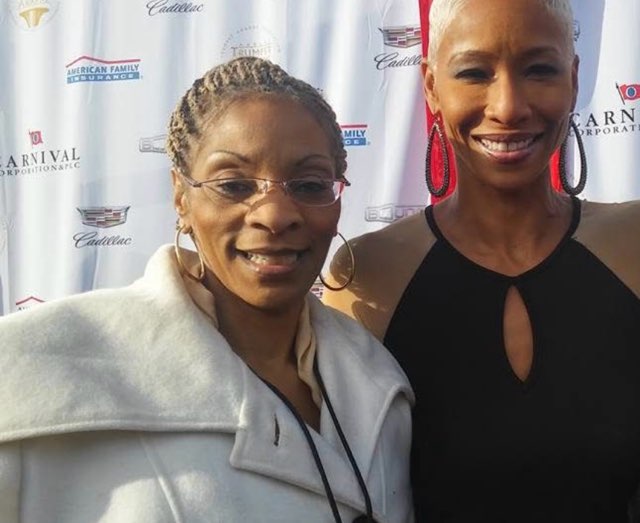 Two smiling women together in front of a Cadillac, American Family Insurance and Carnival step-and-repeat