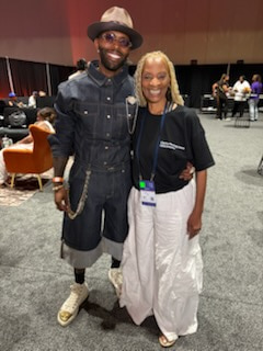 Two smiling people together at a professional event, one wearing a lanyard and badge